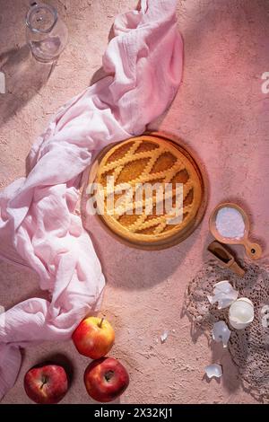 Köstlicher traditioneller Apfelkuchen mit Apfelfrüchten und Zutaten für ihn auf Steinoberfläche, flach gelegen, Blick von oben Stockfoto