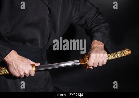 Der Samurai mit einem japanischen Katana-Schwert. Foto eines Kriegers in schwarzer Kleidung in schwachem Tastenfeld mit selektivem Fokus Stockfoto