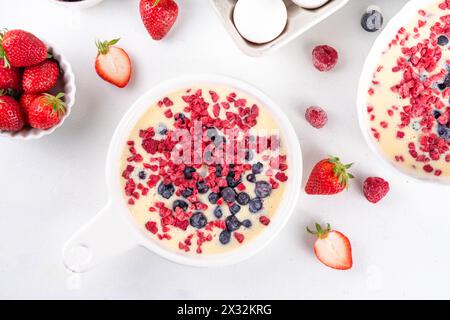 Kochen Herstellung von gebackenem Joghurt gesundes Dessert. Frau Hand kochen Ofen gebacken griechischer Joghurt Dessert mit frischen gefrorenen Beeren, auf weißem Küchentisch, mit Stockfoto