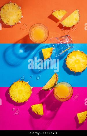 Ananasstücke und Ananassaft auf farbenfrohem Hintergrund. Tropisches Urlaubskonzept. Flache Lage, Draufsicht Stockfoto