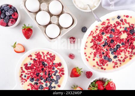 Kochen Herstellung von gebackenem Joghurt gesundes Dessert. Frau Hand kochen Ofen gebacken griechischer Joghurt Dessert mit frischen gefrorenen Beeren, auf weißem Küchentisch, mit Stockfoto
