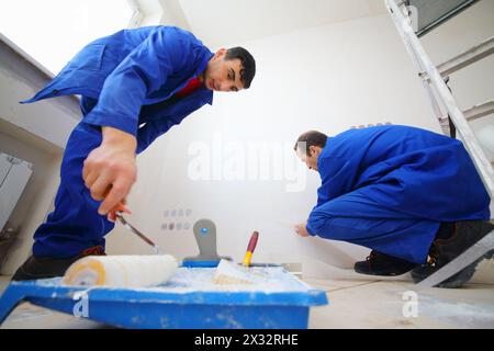 Arbeiter in blauem Leim lackiert Fiberglas und Malwänden in neuer Wohnung Stockfoto