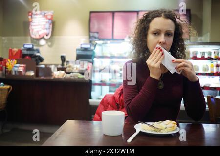 Schöne Frau wischt sich den Mund mit einer Serviette in einem kleinen Restaurant ab Stockfoto