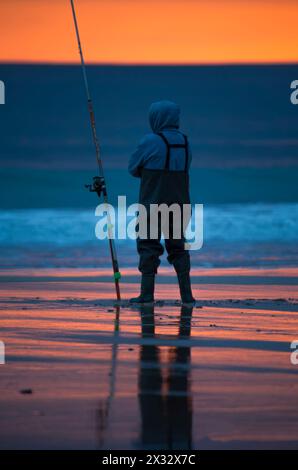 Pescador en la playa al atardecer Stockfoto