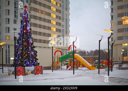 RUSSLAND, MOSKAU - 14. JAN 2014: Ein modernes Haus mit Spielplatz und Weihnachtsbaum auf dem Hof im Wohnkomplex Elk Island Stockfoto