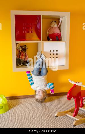 Kleines Mädchen im Kinderzimmer, das kopfüber im Haus sitzt Stockfoto