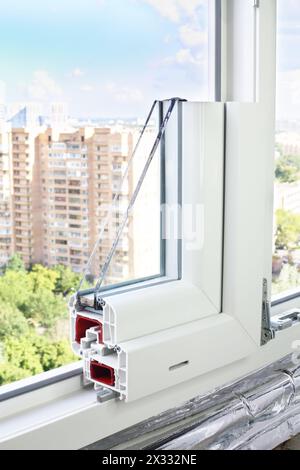 Beispiel eines PVC-Fensters in einer Fensteröffnung mit Blick auf den Park und die Gebäude Stockfoto