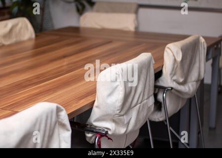 Das Zimmer verfügt über einen Hartholztisch mit bequemen weißen Stühlen zum Sitzen. Die Holzbeize verleiht dem Boden Wärme und schafft eine gemütliche Atmosphäre Stockfoto