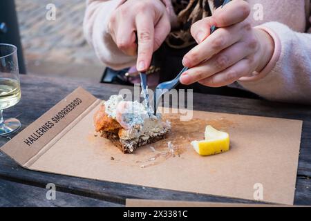 Kopenhagen, Dänemark - 5. April 2024: Frau isst im beliebten Café Hallernes Smørrebrød. Stockfoto