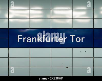 U-Bahn-Schild Frankfurter Tor in Berlin. Der Name des Standorts für öffentliche Verkehrsmittel ist auf einem dunkelblauen Hintergrund an einer gefliesten Wand. Stockfoto