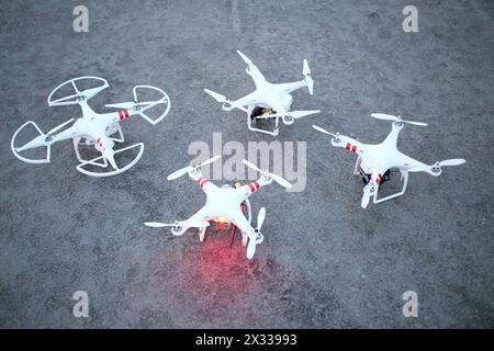 MOSKAU, RUSSLAND - 27. April 2014: Vier weiße Quadcopter mit Propellern auf Asphalt am Abend Stockfoto