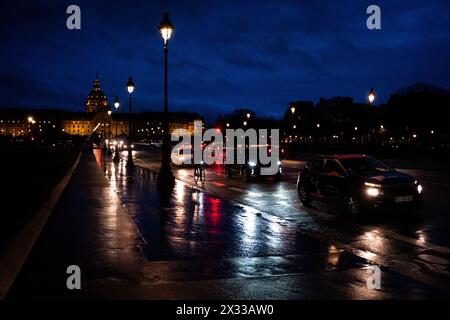 Fahrrad- und Autoverkehr auf der Esplanade des Invalides bei Einbruch der Dunkelheit, mit dem Hotel des Invalides, einer Gruppe von Armeemuseen und einer Kirche, in der das to untergebracht ist Stockfoto