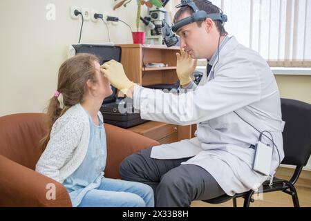 Augenarzt untersucht die Augen eines Teenagers mit einer Lupe Stockfoto