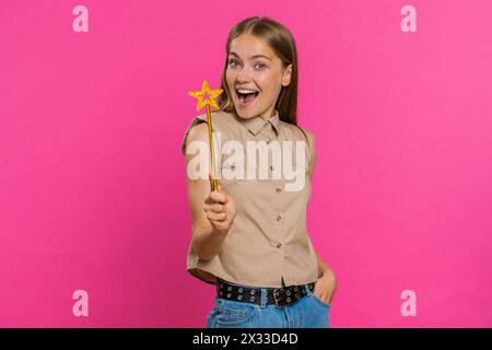 Zauberhexe junge Frau, die mit Zauberstab-Feenstab Gesten, Wünsche wahr werden lassen, Zauberzauber wirken, Feiertagsrabatt werben. Hübsches Mädchen, isoliert auf rosa Studio-Hintergrund Stockfoto