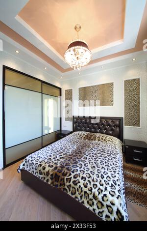 Modernes Zimmer im griechischen Stil mit Leopardendruck an den Wänden und am Bett Stockfoto