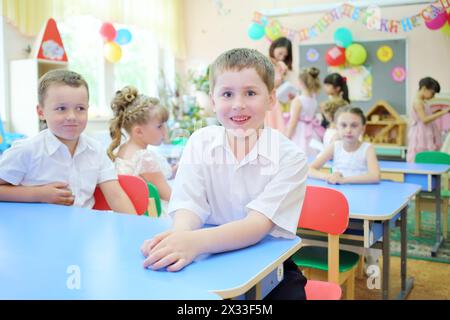 Porträt eines lächelnden Jungen in einer Gruppe mit sieben Kindern und Erzieher im Kindergarten Stockfoto