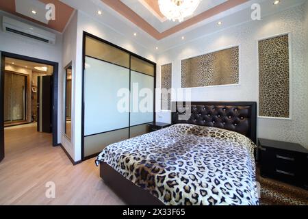 Luxuriöses Schlafzimmer im griechischen Stil mit Leopardendruck an den Wänden und am Bett Stockfoto