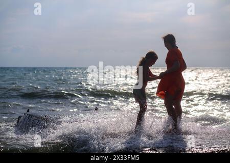 Mutter und Tochter stehen auf dem Dock in den Wellen Stockfoto