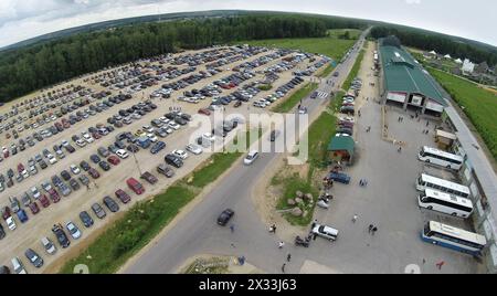 RUSSLAND, BOROVSK - 13. Juni 2014: Großer Parkplatz mit vielen Autos in der Nähe des Kulturkomplexes Ätnomir am Sommertag. Luftaufnahme. Foto mit Geräuschen von Action ca. Stockfoto