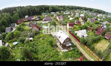 RUSSLAND, BOROVSK – 13. Juni 2014: Luftaufnahme von Hütten in der Nähe des großen Waldes. Foto mit Rauschen von der Action-Kamera Stockfoto