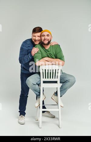 Zwei Männer umarmen sich liebevoll an einem Stuhl und zeigen Liebe und Zweisamkeit in einem intimen Moment. Stockfoto