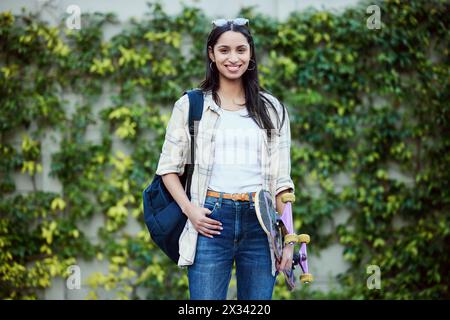 Porträt, Universität und Frau auf dem Campus mit Skateboard für Bildung, Lernen und Wissen. Student, Skater und Person mit Rucksack für Glück Stockfoto