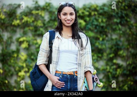 Porträt, College und Frau auf dem Campus mit Skateboard für Bildung, Lernen und Wissen. Student, Skater und Person mit Rucksack für Glück Stockfoto