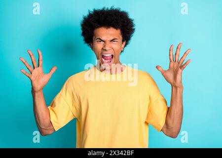Porträt des wütenden wütenden Mannes mit Afrofrisur tragen übergroßes T-Shirt lauter Schrei, der Palmen auf blaublauem Hintergrund aufhebt Stockfoto