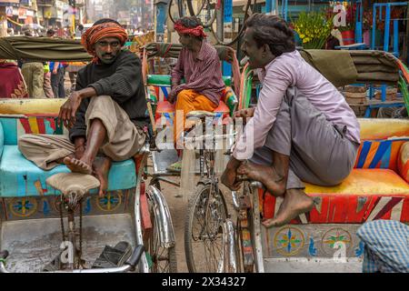 Drei geparkte Rikscha-Fahrer unterhalten sich in Varanasi, Indien Stockfoto