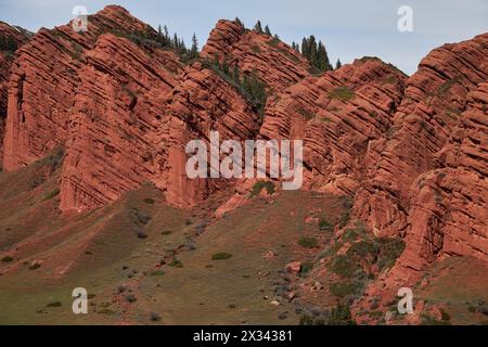 Rote Felsen sieben Ochsen, Nadelbäume auf dem Felsen, 7 Stiere, Schlucht Jety-Oguz. Touristische Lage, Reiseziel Ort, Kirgisistan Wahrzeichen Jeti Stockfoto