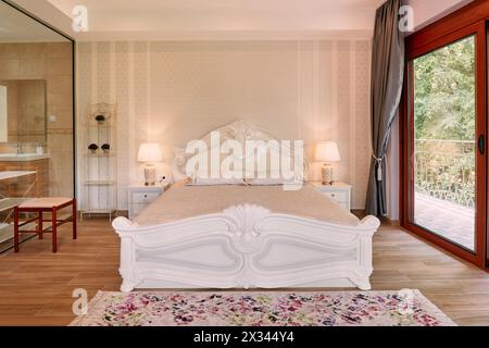 Weißes Doppelbett in einem Hotelzimmer mit Panoramafenster und Glastrennwand im Badezimmer Stockfoto