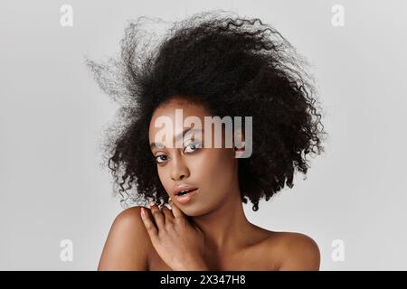 Eine junge afroamerikanische Frau mit lockigem Haar posiert für ein Porträt, zeigt ihr luxuriöses Haar. Stockfoto