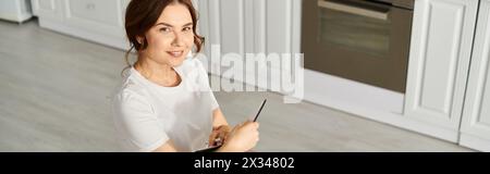 Frau mittleren Alters mit Handy in stilvoller Küche. Stockfoto