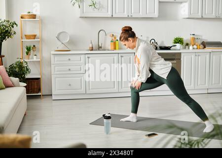 Eine Frau mittleren Alters spielt anmutig eine Yoga-Pose auf einer Yogamatte zu Hause. Stockfoto