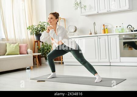 Eine Frau mittleren Alters spielt anmutig eine Yoga-Pose in ihrem gemütlichen Wohnzimmer. Stockfoto