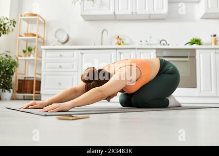 Eine Frau mittleren Alters spielt anmutig Yoga-Pose auf dem Boden zu Hause. Stockfoto