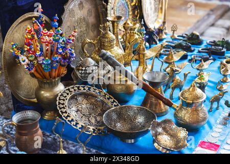 Auswahl eines Straßenbazars in Buchara. Auf der Theke stehen Gerichte aus Messing mit geprägten Mustern und andere Souvenirs Stockfoto