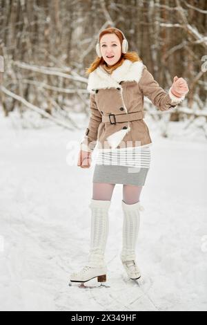 Rothaariges Teenager-Mädchen mit Zahnspangen auf den Schlittschuhen im Winterpark. Stockfoto