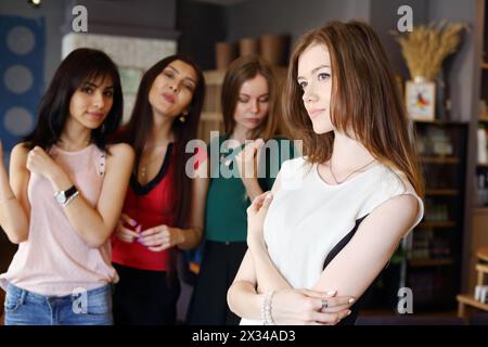 Junge schöne Frau posiert im Café und drei Mädchen aus dem Fokus Stockfoto