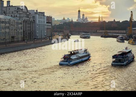 MOSKAU, RUSSLAND - 20. August 2016: Vergnügungsboote mit Inschriften Moskau am Fluss Moskva und am Kreml bei Sonnenuntergang. Stockfoto