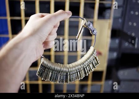 Die männliche Hand hält einen Haufen Schlüssel vor der Gittertür aus Eisen. Stockfoto