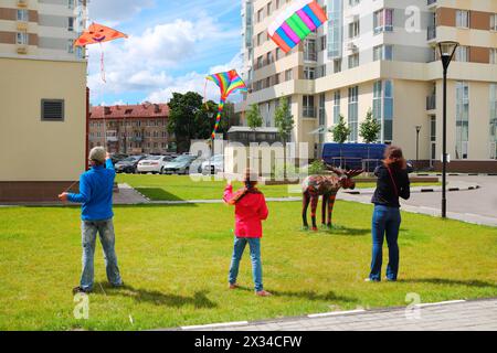 Mutter mit Kindern startet Drachen auf dem Boden in der Nähe des Sommers Stockfoto