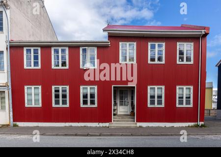 Traditionelles isländisches, eisenverkleidetes, rotes Wohnhaus mit weißen Fensterrahmen, verkleidet mit Wellblechen in Reykjavik, Island. Stockfoto