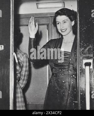 Königin Elisabeth II. Winkt aus einem Zugfenster, als sie nach einem Urlaub in Balmoral Castle nach London zurückkehrt, auf einem Foto von etwa 1952. Nach ihrem Aufstieg von der Prinzessin zur Königin im Februar 1952 erhöhten sich Elisabeths Pflichten erheblich. Dieses Bild fängt die neue Königin ein, die ihre erste Pause von ihrer neu entdeckten königlichen Verantwortung genießt. Stockfoto