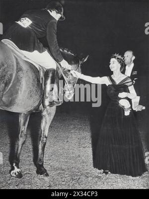 Königin Elizabeth II. Wird auf der Windsor Horse Show im Juli 1952 gefangen genommen und präsentiert der Reiterin Patricia Ann Moss eine Rosette für ihren Sieg in der Ladies versus Gentleman Team Jumping Championship. Bekannt für ihre Liebe zu Pferden, besuchte Elizabeth häufig Pferdeshows. Patricia Ann Moss zeichnete sich später als eine der erfolgreichsten weiblichen Rallyefahrerinnen aller Zeiten aus. Stockfoto