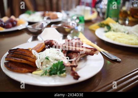 Fleischrippchen auf Teller mit Zwiebeln und Petersilie in Nahaufnahme im Café, flacher freiraum Stockfoto