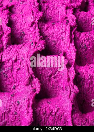 Gefrorenes Eis mit Himbeergeschmack – Vollformatdetail des Sorbets. Nahaufnahme einer rosafarbenen Oberflächenstruktur von Eis gefüllt mit Stücken gemischter Früchte. Stockfoto