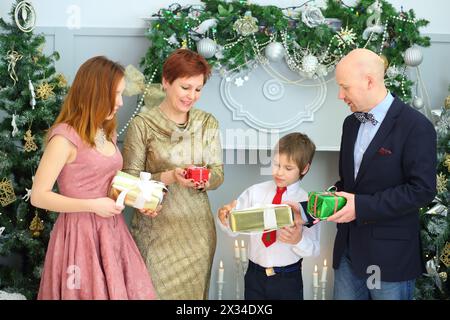 Ehemann, Frau, Sohn und Tochter halten während der weihnachtszeit Geschenke im Zimmer Stockfoto