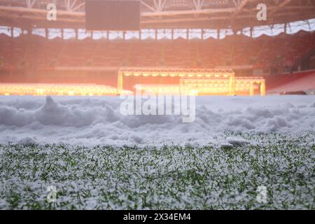 Nahaufnahme von Schnee auf grünem Feld im Fußballstadion mit Lampen Stockfoto