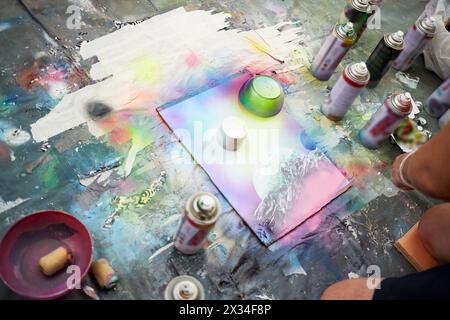 Der junge Mann zeichnet ein Bild mit Sprühfarben. Stockfoto